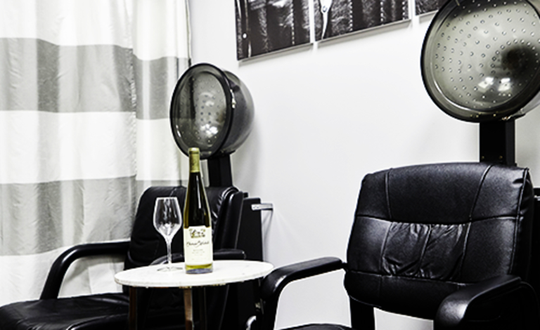 Find a stylist two blow dry chairs and a bottle and glass of wine